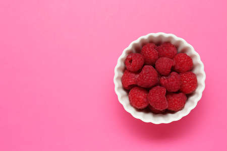 Bowl of fresh delicious raspberries on pink background, top view. Space for textの写真素材