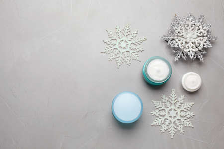 Flat lay composition with cosmetic products and snowflakes on light gray table, space for text. Winter skin careの写真素材