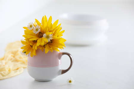 Cup with beautiful flowers on white table. Space for textの写真素材