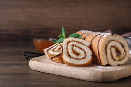 Tasty cake roll with jam on wooden table, space for text