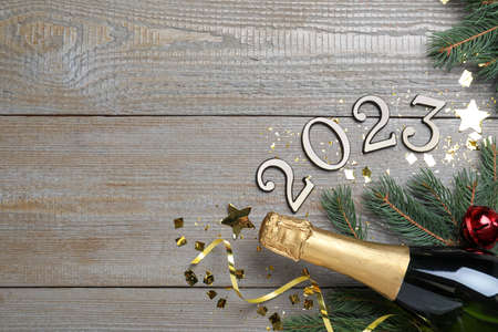 Happy New Year 2023! Flat lay composition with bottle of sparkling wine on wooden table, space for...