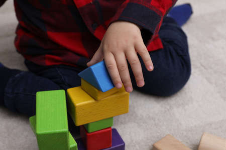 Little child playing with building blocks on carpet, closeupの写真素材