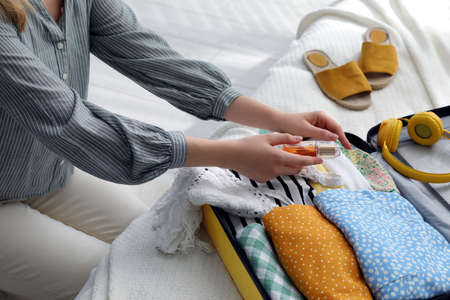 Woman packing suitcase for trip on bed, closeupの写真素材