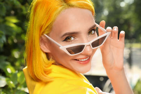 Beautiful young woman with bright dyed hair in park