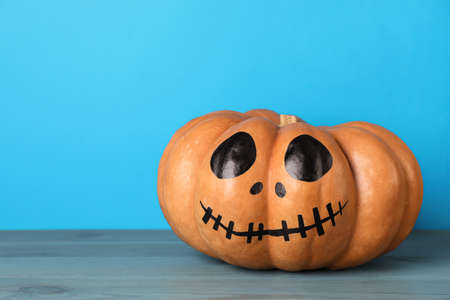 Pumpkin with drawn spooky face on light blue background, space for text. Halloween celebrationの写真素材