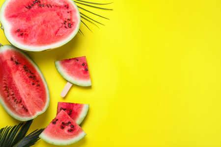 Delicious ripe watermelon and tropical leaves on yellow background, flat lay. Space for textの写真素材