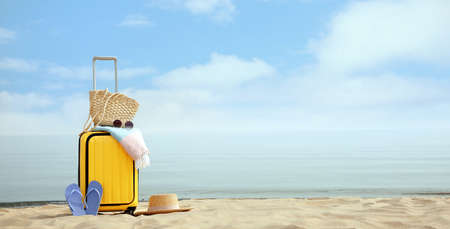 Yellow suitcase with beach items on sandy seashore, space for textの写真素材