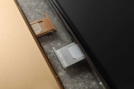 Mobile phones with Sim cards in trays on gray table, closeupの写真素材