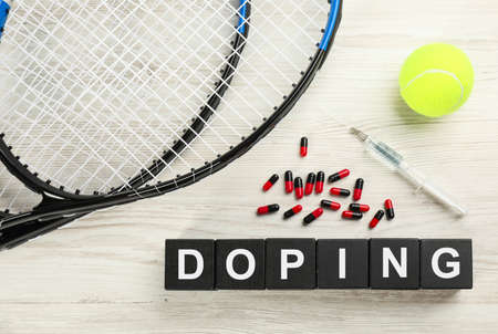 Black cubes with word Doping, tennis rackets, ball and drugs on white wooden background, flat layの写真素材