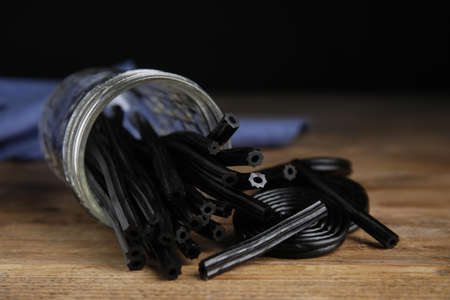 Tasty black liquorice candies on wooden table, closeupの写真素材