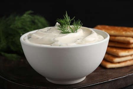 Tasty creamy dill sauce in bowl on wooden board, closeupの写真素材