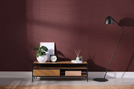 Elegant room interior with wooden cabinet and floor lamp near brown wallの写真素材