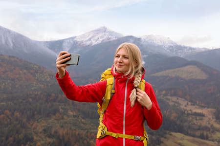 Happy young woman taking selfie with phone in mountainsの写真素材