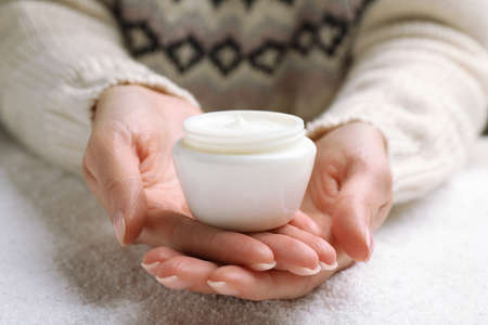 Woman with jar of hand cream over snow, closeupの写真素材