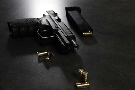Handgun, magazine and bullets on gray table