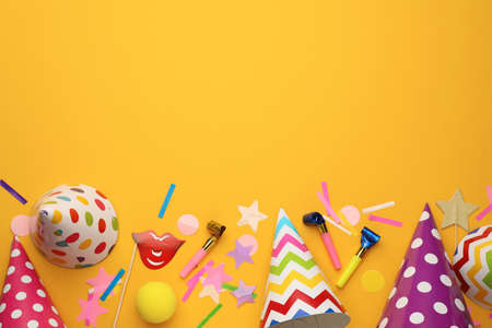 Flat lay composition with party hats and other festive items on orange background. Space for text