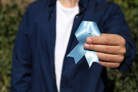 Man holding light blue ribbon outdoors, closeup. World Diabetes Dayの写真素材