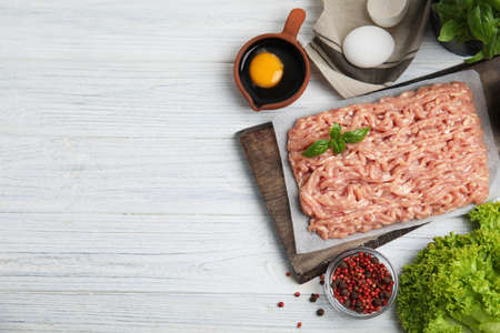 Raw chicken minced meat and ingredients on white wooden table, flat lay. Space for text