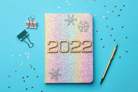 Bright planner, pen, stationery, decorative snowflakes and confetti on light blue background, flat...