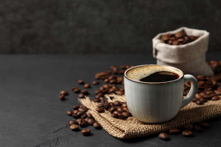 Cup of aromatic coffee and beans on black table. Space for textの写真素材