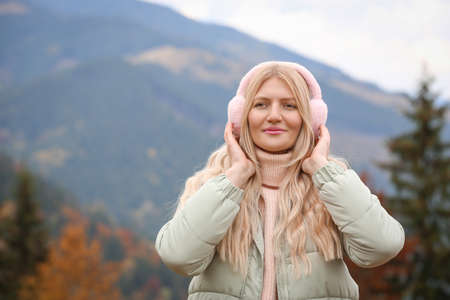 Young beautiful woman wearing warm earmuffs in mountainsの写真素材