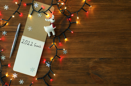 Inscription 2022 Goals written in planner and Christmas decor on wooden background, flat lay with...