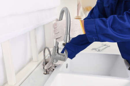 Plumber repairing water tap in kitchen, closeupの写真素材