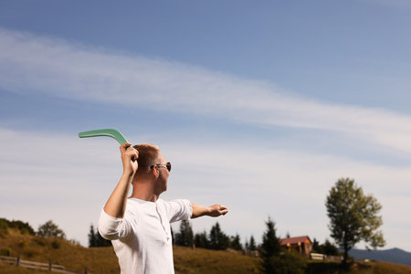 Man throwing boomerang outdoors on sunny day. Space for textの写真素材