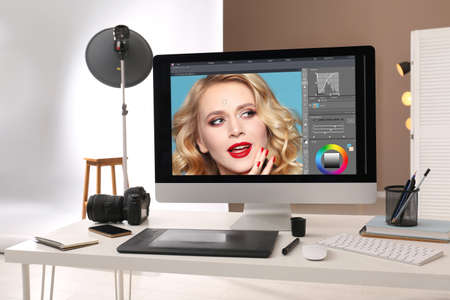 Retoucher's workplace. Computer with photo editor application, camera, smartphone and graphic tablet...