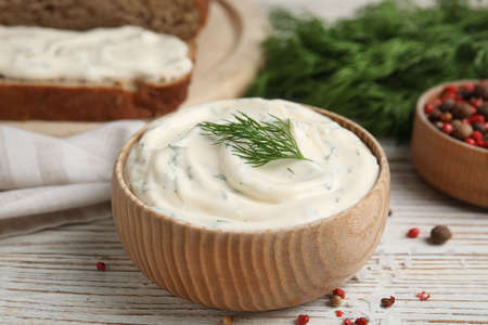 Tasty creamy dill sauce in bowl on white wooden table, closeupの写真素材