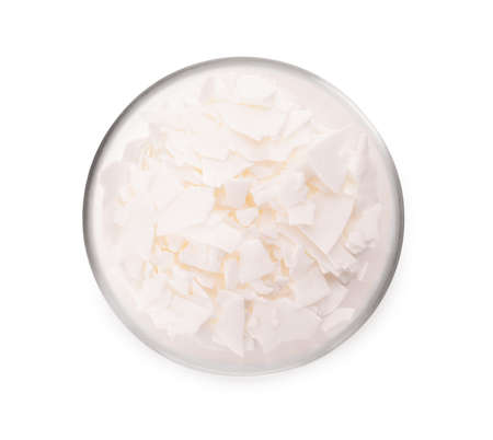 Wax flakes in glass bowl on white background, top view. Homemade candle material