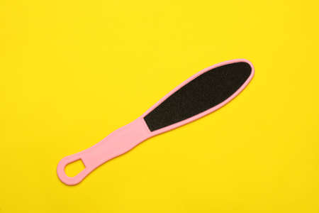 Pink foot file on yellow background, top view. Pedicure toolの写真素材