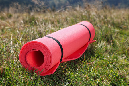 Rolled pink soft sleeping pad on grassの写真素材