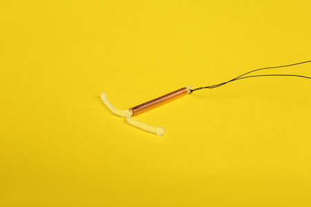 T-shaped intrauterine birth control device on yellow backgroundの写真素材