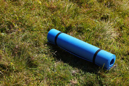 Rolled blue soft sleeping pad on grassの写真素材