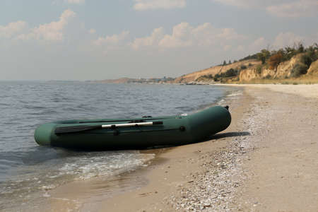 Inflatable rubber fishing boat on sandy beach near seaの写真素材