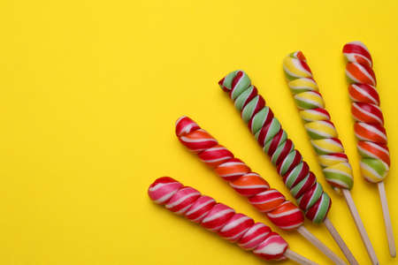 Delicious lollipops on yellow background, flat lay. Space for textの写真素材