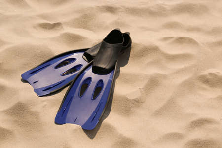 Pair of blue flippers on sand. Space for textの写真素材