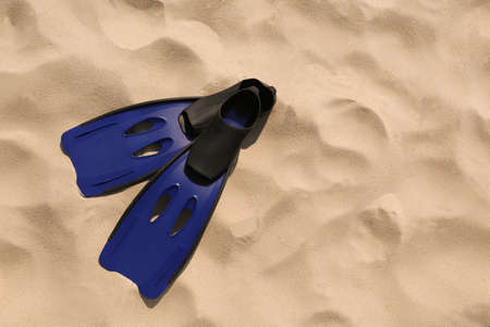 Pair of blue flippers on sand, top view. Space for textの写真素材