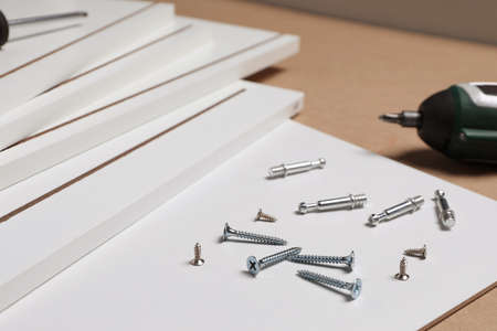 White furniture assembly parts and different metal fasteners on brown backgroundの写真素材