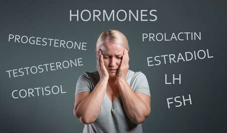 Hormones imbalance. Upset mature woman and different words on gray backgroundの写真素材