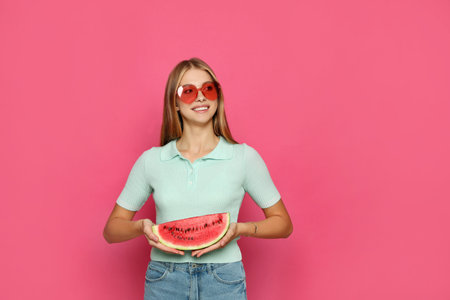 Beautiful girl with slice of watermelon on crimson backgroundの写真素材