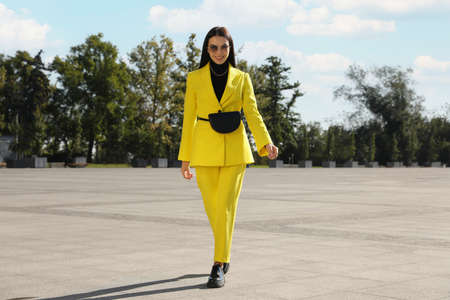 Beautiful young woman with stylish waist bag on city streetの写真素材