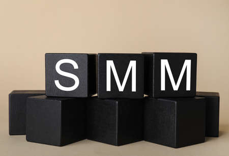Black cubes with abbreviation SMM (Social media marketing) on beige backgroundの写真素材