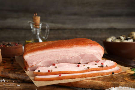 Delicious smoked bacon with spices on wooden table, closeupの写真素材