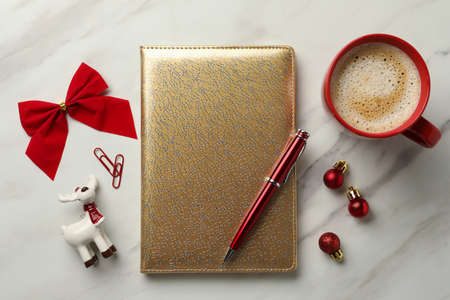 Stylish planner, cup of aromatic coffee and Christmas decor on white marble background, flat lay....