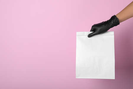 Woman holding paper bag on pink background, closeup. Space for text