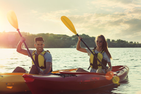 Couple in life jackets kayaking on river at sunset. Summer activityの写真素材