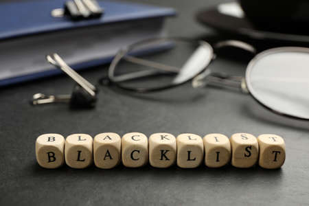 Wooden cubes with word Blacklist and office stationery on black desk, closeupの写真素材