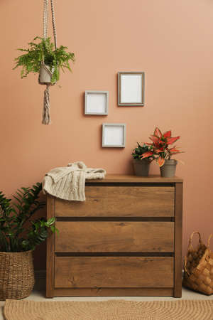 Wooden chest of drawers near brown wall at home. Interior design
